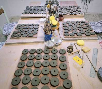 A table showing five plates full with clay disks ready to be cooked